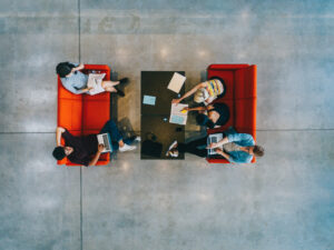 Junge Leute sitzen an einem Tisch und lernen in der öffentlichen Bibliothek. Studenten mit Büchern und Laptop von oben
