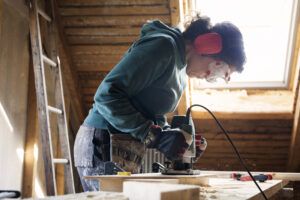 Eine Frau benutzt ein Elektrowerkzeug bei der Renovierung eines alten Dachbodens